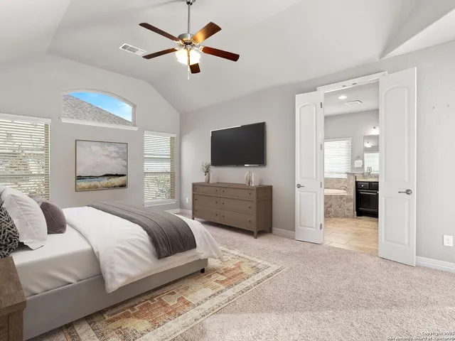 a spacious bedroom with a bed and a flat screen tv