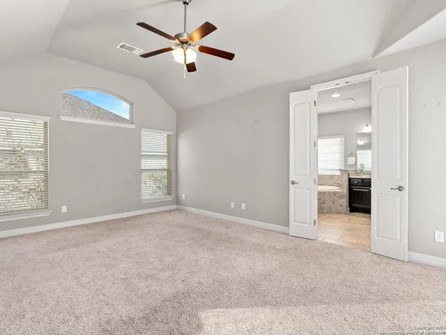 an empty room with windows and a chandelier fan