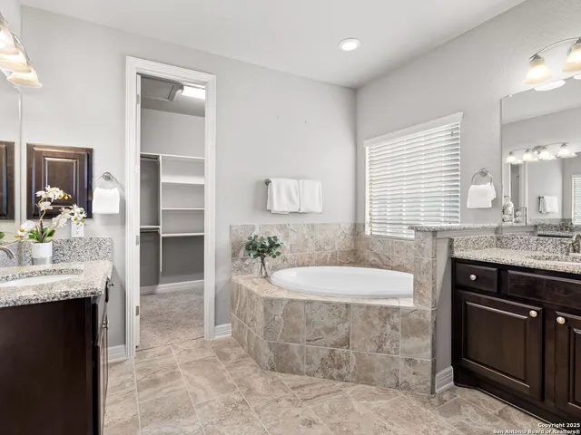a spacious bathroom with a granite countertop sink a mirror and a bathtub
