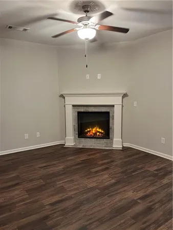a view of an empty room with wooden floor fireplace and a window