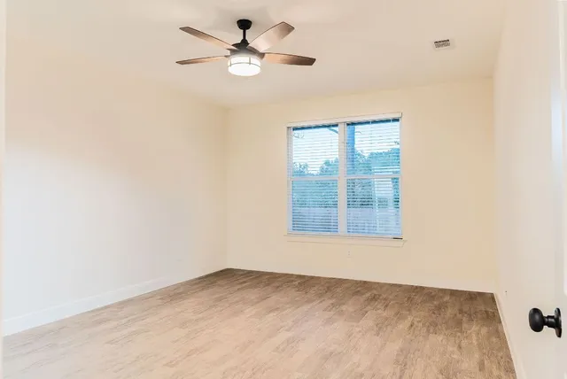 an empty room with windows and fan