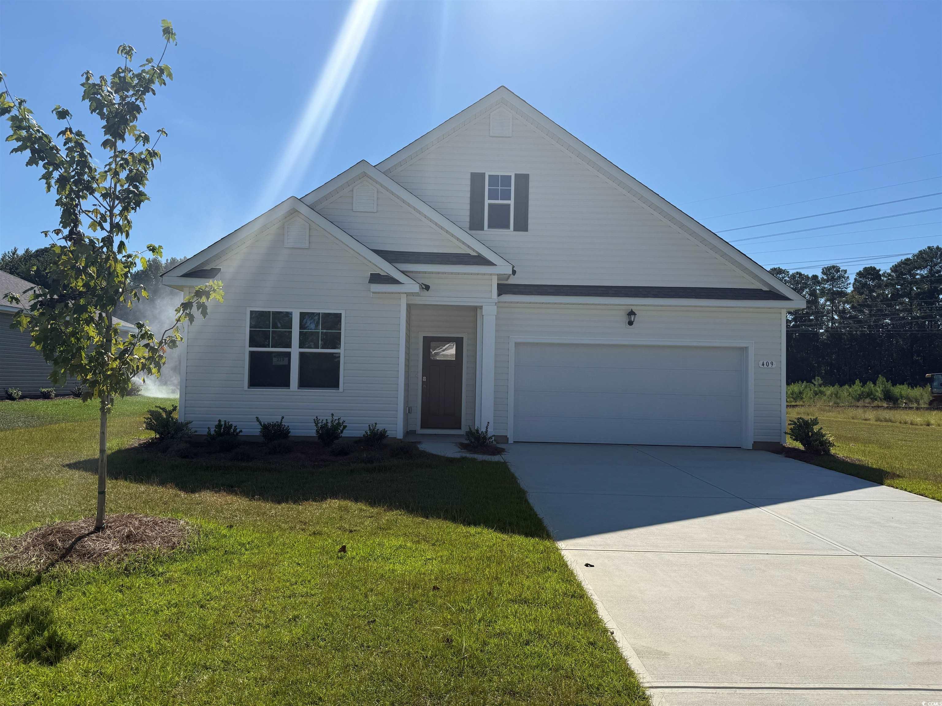 View of front facade with a garage, a front yard, and driveway