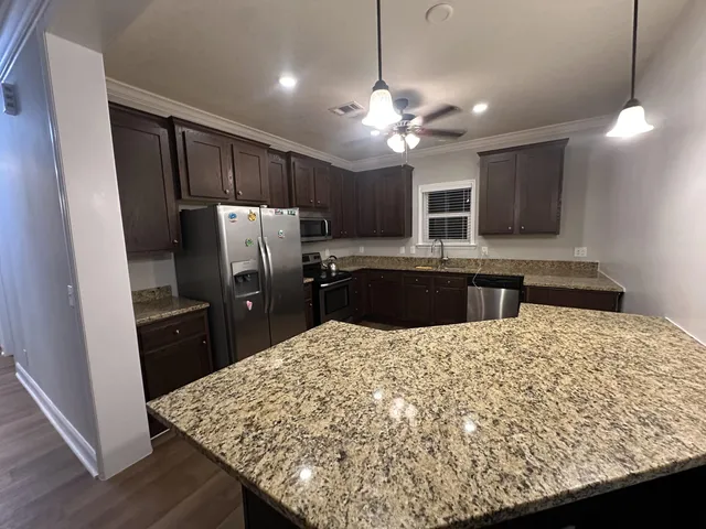 a kitchen with kitchen island a counter top space appliances and cabinets