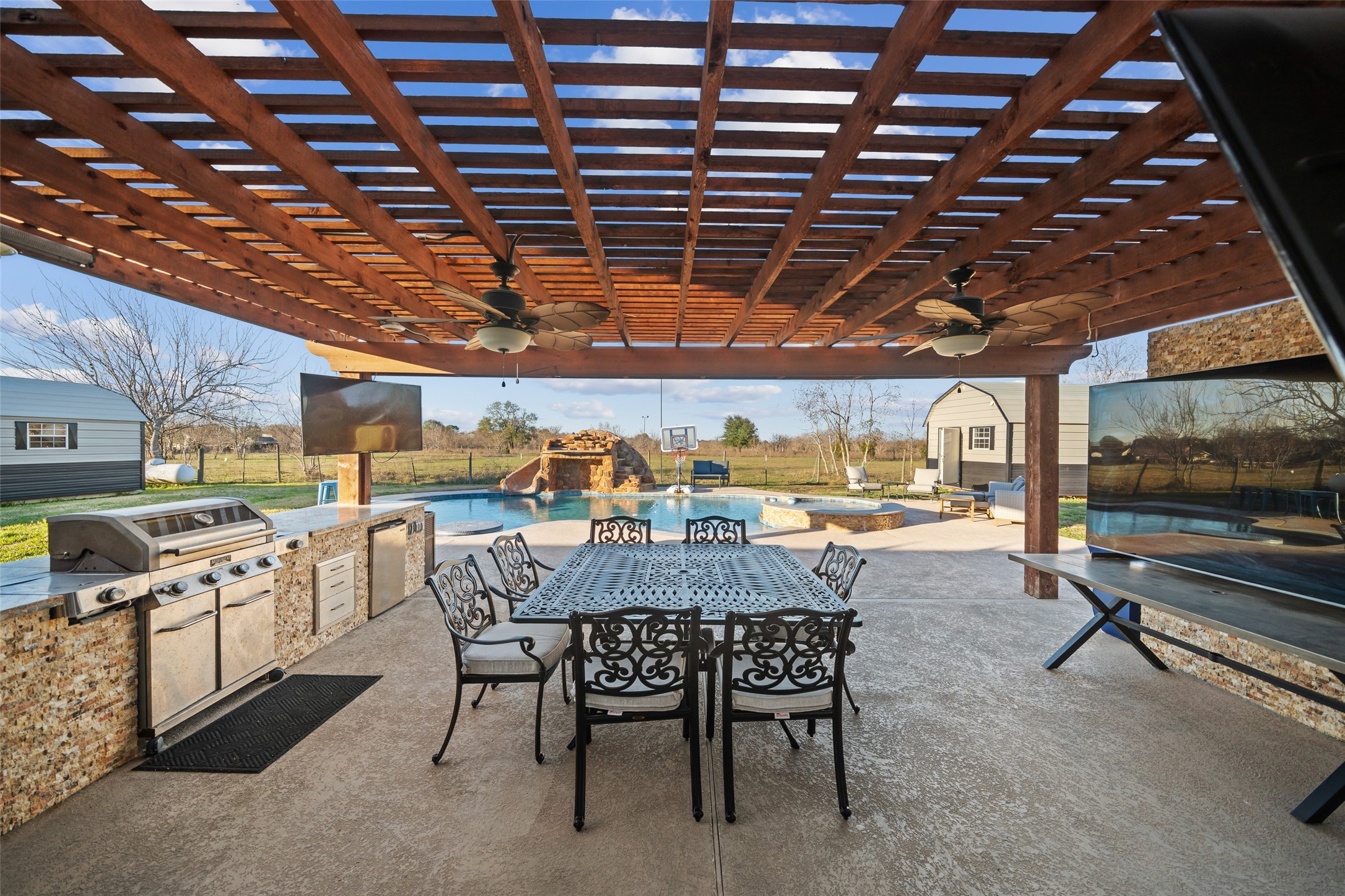 43910 Highway 290 Business Prairie View, TX 77484 - Photo 33 of 49 Large covered patio with dual ceiling fans, outdoor kitchen, and open sightlines to the pool.