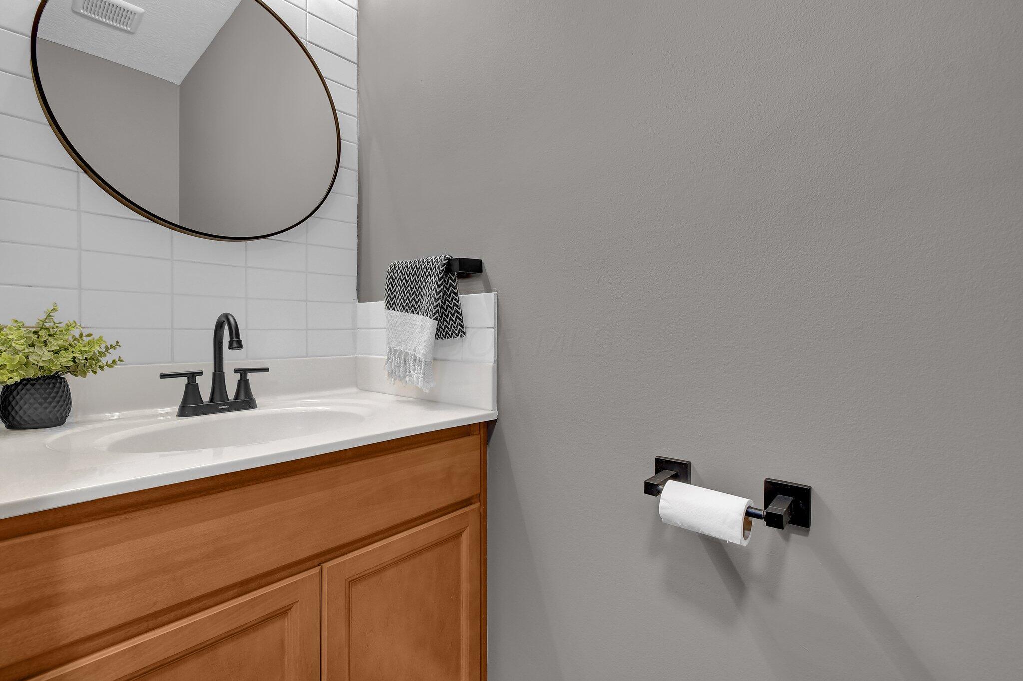 916 Rooks Circle Sunbury, OH 43074 - Photo 13 of 39 First floor powder room has an tile accent wall and upgraded black hardware.