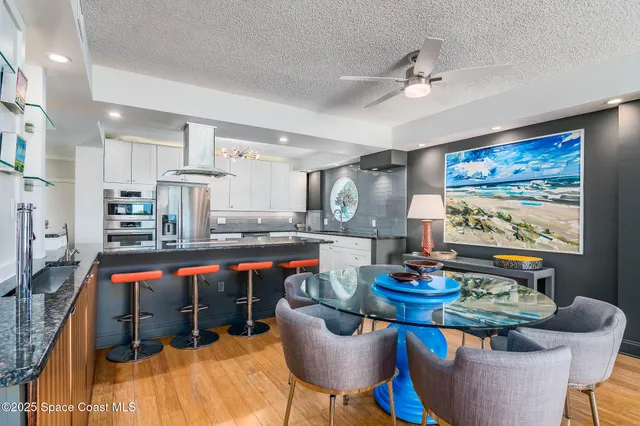 a large white kitchen with a large island wooden floor and stainless steel appliances