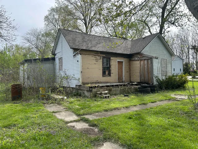 a backyard of a house with plants and large tree