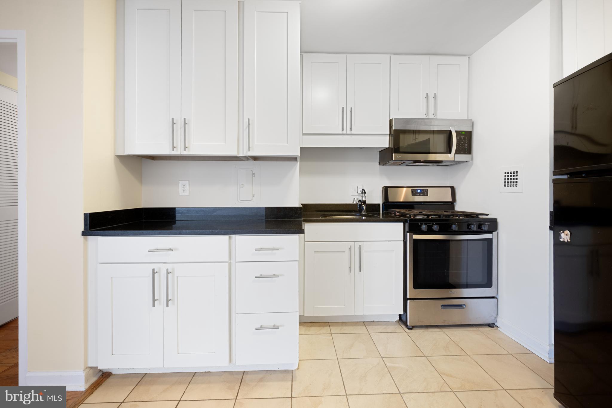 922 24th Street Northwest, Unit 809 Washington, DC 20037 - Photo 6 of 17 a kitchen with white cabinets and stainless steel appliances