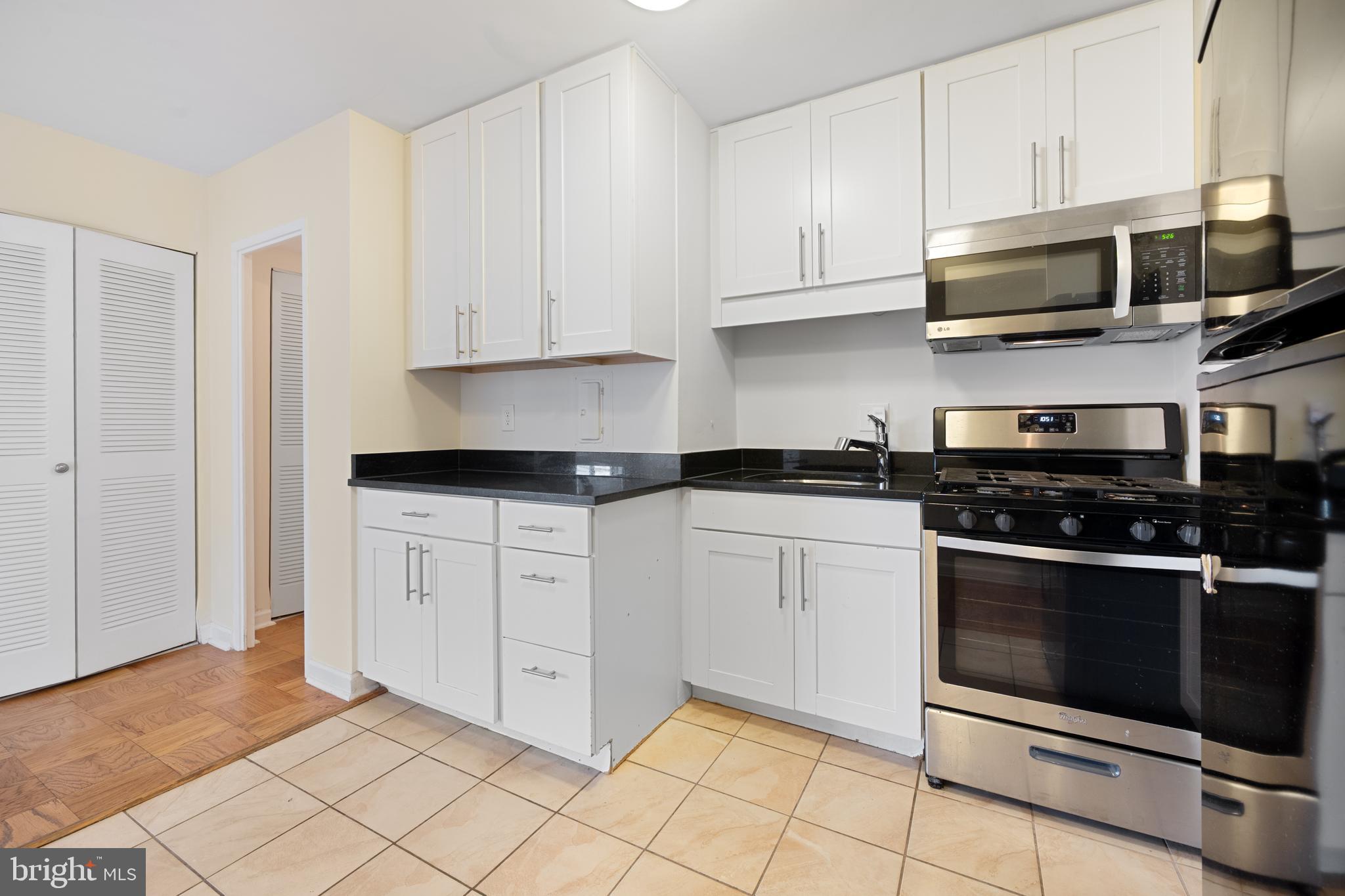922 24th Street Northwest, Unit 809 Washington, DC 20037 - Photo 9 of 17 a kitchen with stainless steel appliances granite countertop a stove a microwave and a white cabinets