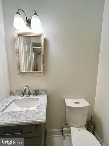a bathroom with a granite countertop toilet sink and mirror