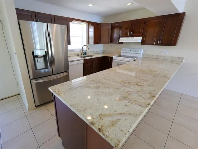 a kitchen with kitchen island a counter top space a sink a stove a refrigerator and cabinets