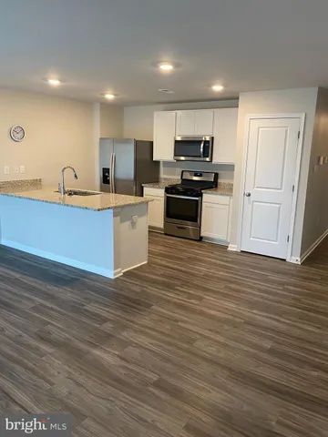 a kitchen with granite countertop a sink cabinets and stainless steel appliances