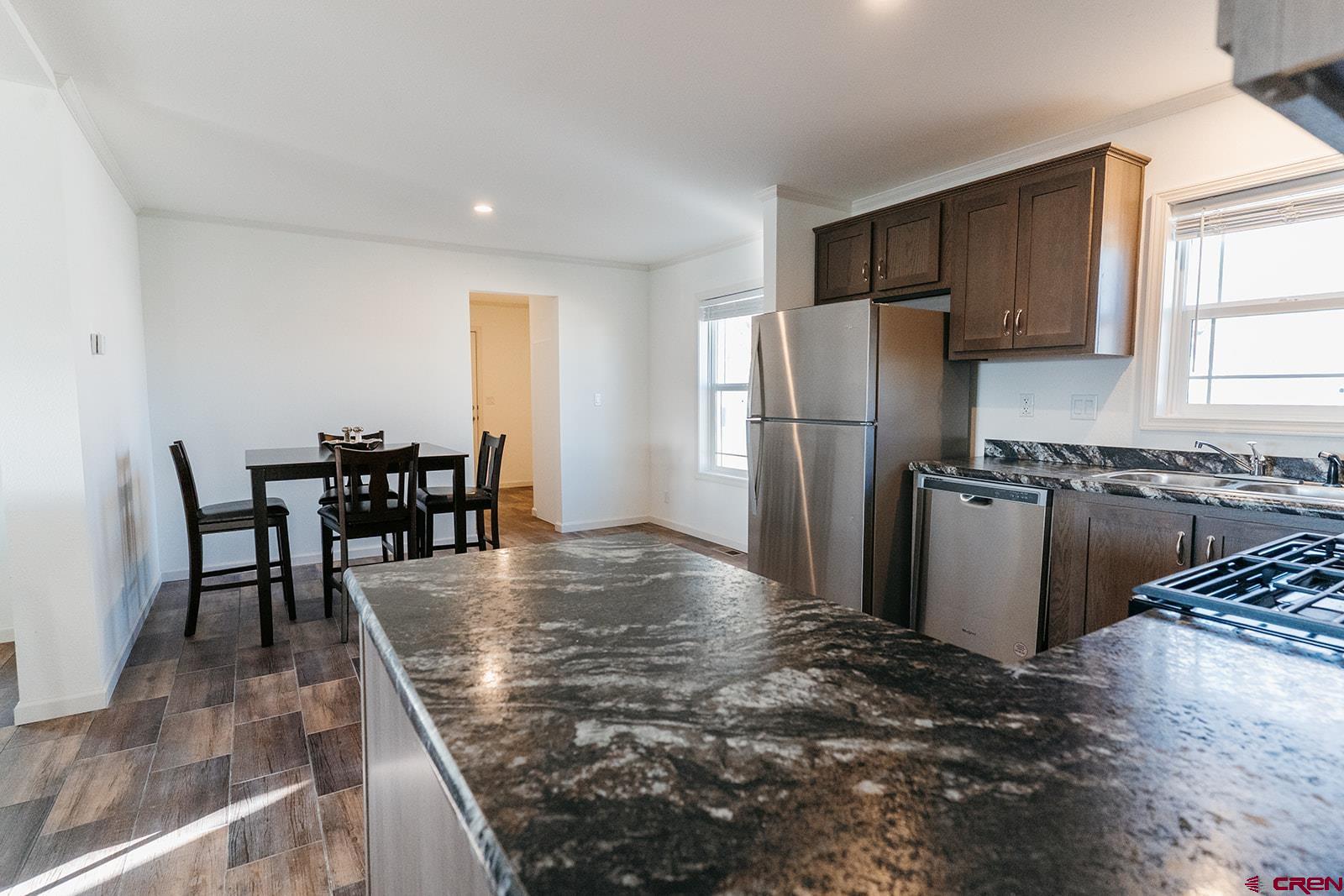 62650 Lasalle Road, Unit 820 Montrose, CO 81403 - Photo 15 of 29 a kitchen with stainless steel appliances granite countertop a stove a refrigerator a dining table and chairs with wooden floor