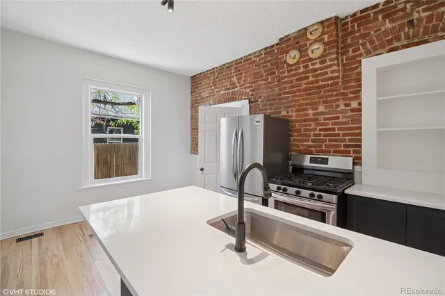 a kitchen with stainless steel appliances kitchen island wooden cabinets a stove a sink and a refrigerator