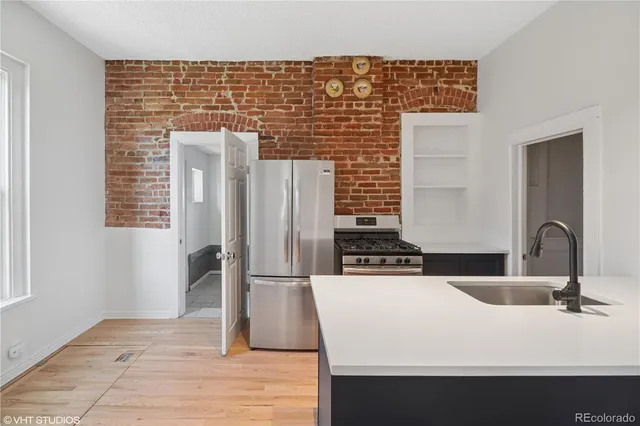 a close view of a sink a counter space and a refrigerator in the kitchen