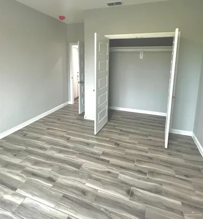 an empty room with chandelier fan and windows