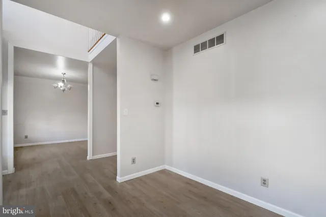 an empty room with wooden floor chandelier and windows