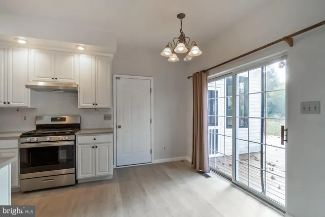 a kitchen with stainless steel appliances granite countertop a refrigerator a sink dishwasher a stove and white cabinets with wooden floor