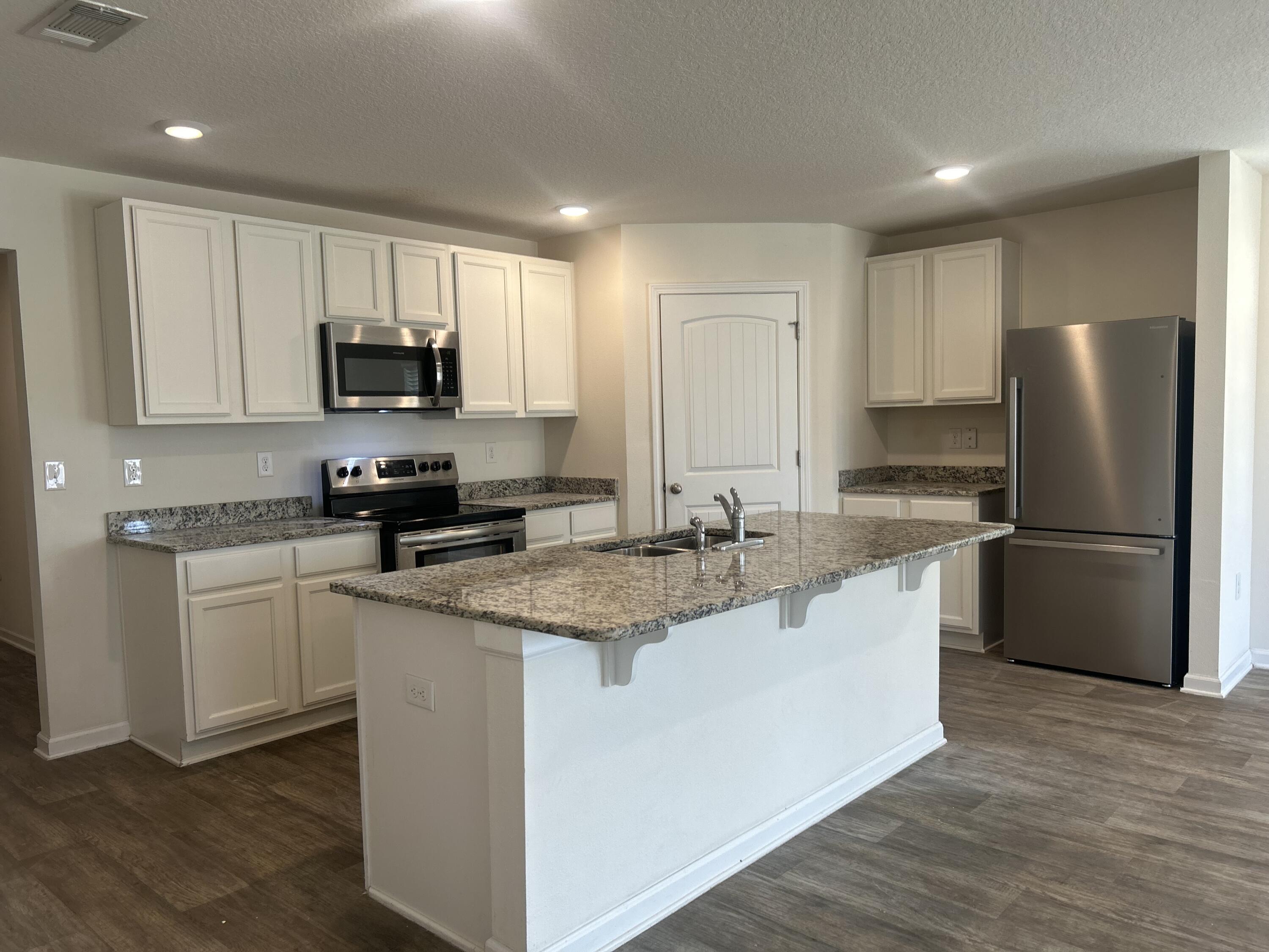 916 Merganser Way Crestview, FL 32539 - Photo 4 of 37 a kitchen with stainless steel appliances granite countertop a refrigerator a sink a stove a microwave and white cabinets