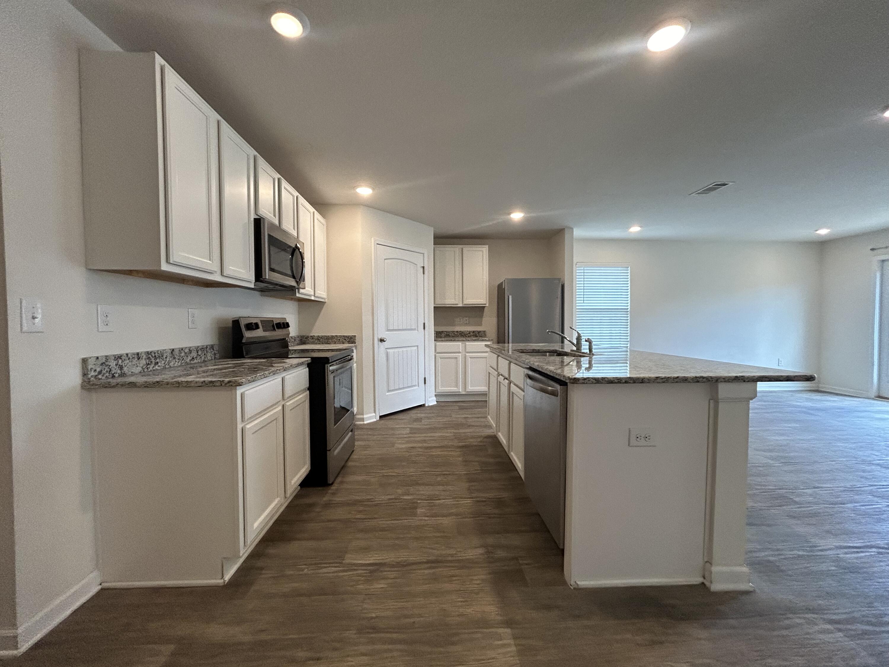 916 Merganser Way Crestview, FL 32539 - Photo 7 of 37 a kitchen with stainless steel appliances kitchen island granite countertop a stove a sink and a refrigerator