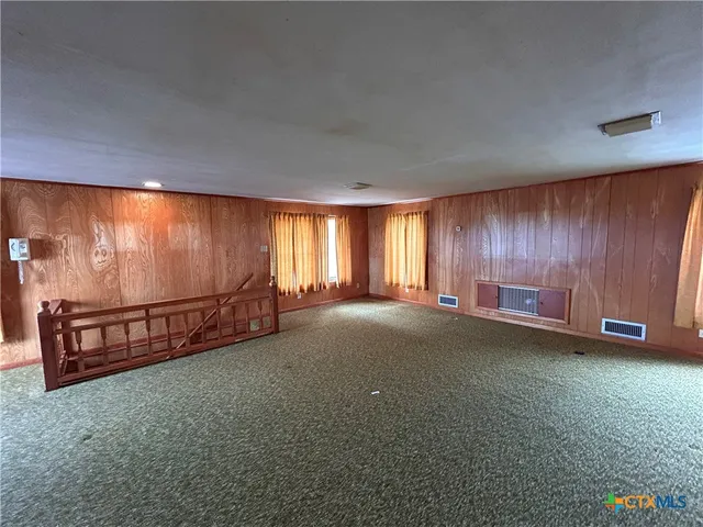 a view of an empty room with window and chandelier