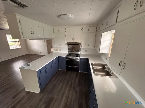 a kitchen with granite countertop wooden cabinets stove top oven and sink