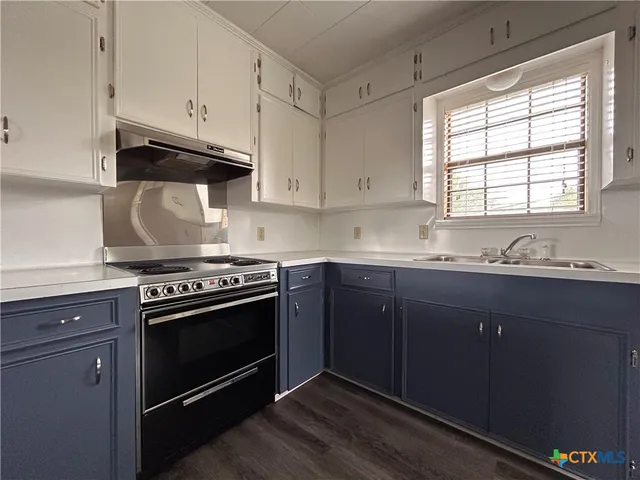 an empty room with wooden floor cabinet and windows