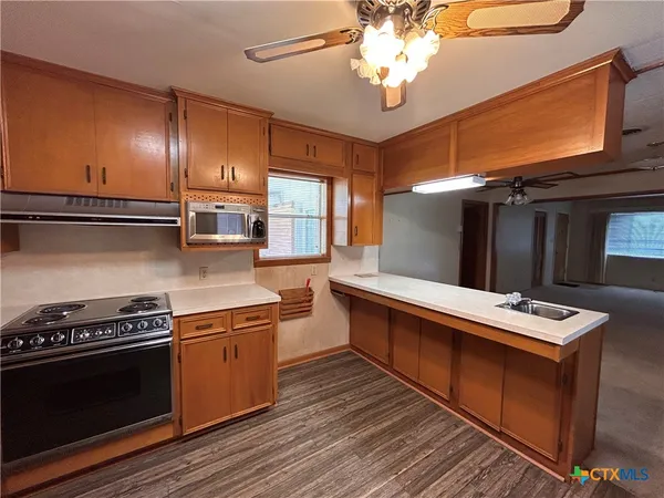 a kitchen with stainless steel appliances granite countertop a stove a sink dishwasher and a refrigerator with wooden floor