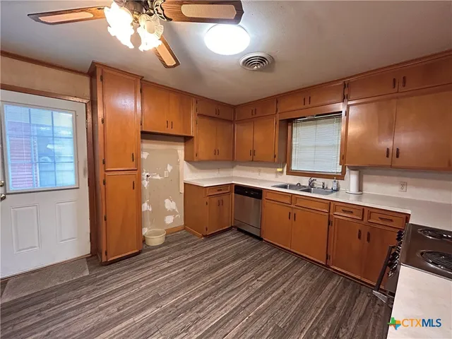 a kitchen with stainless steel appliances granite countertop a sink a stove a refrigerator and island with wooden floor