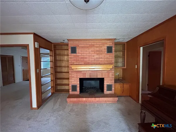 a view of an empty room with window and fire place