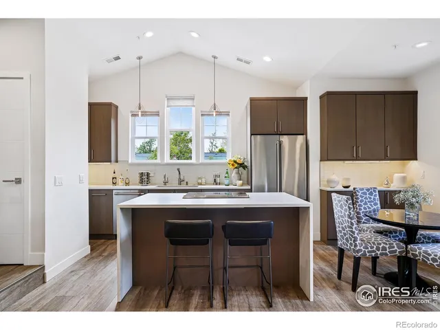 a kitchen with stainless steel appliances a table chairs refrigerator and sink