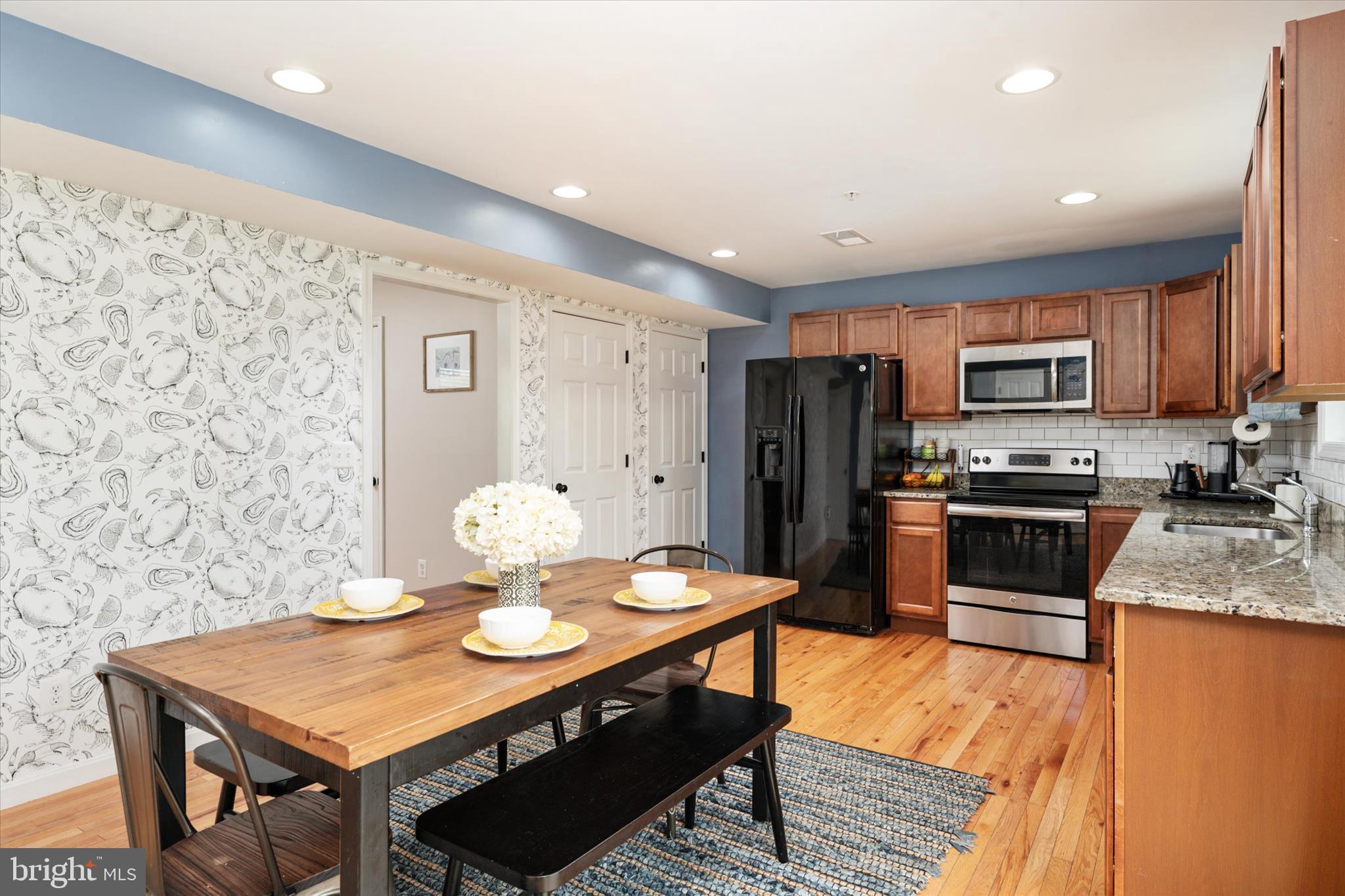 200 Newtown Road Chester, MD 21619 - Photo 16 of 50 a kitchen with stainless steel appliances granite countertop a stove a refrigerator a microwave oven with a dining table and chairs