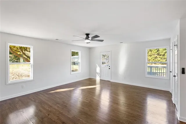 a view of an empty room with a window and wooden floor