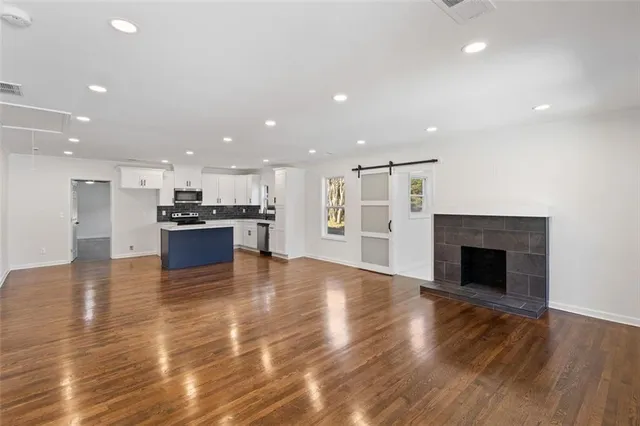 a view of kitchen with kitchen island wooden floor center island and stainless steel appliances