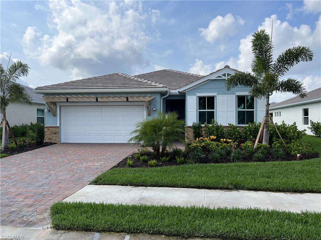 Ranch-style home with decorative driveway, an attached garage, a tiled roof, stucco siding, and stone siding