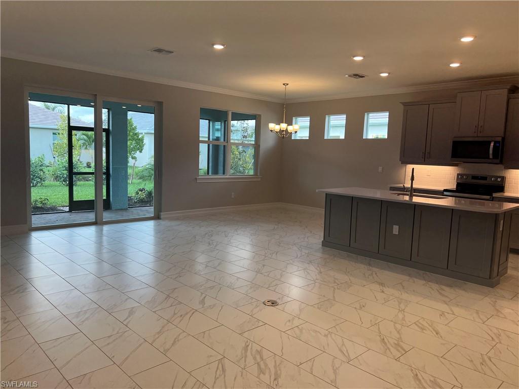 393 Deauville Loop Naples, FL 34114 - Photo 11 of 19 Kitchen featuring stainless steel microwave, range with electric stovetop, a chandelier, baseboards, and crown molding