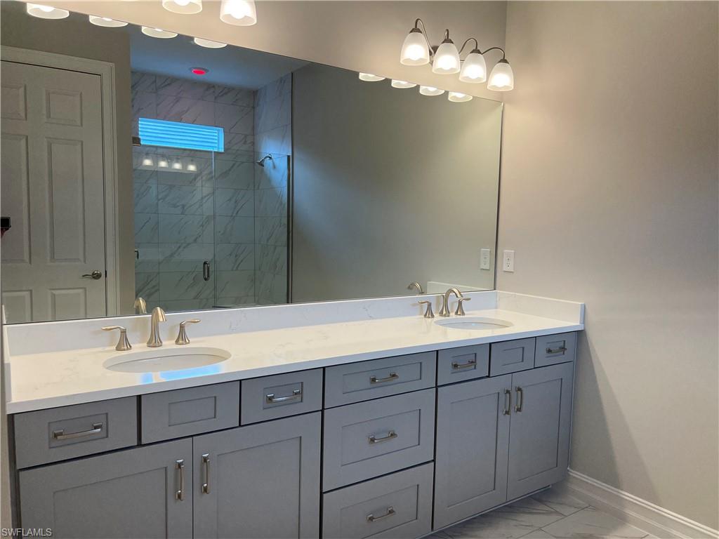 393 Deauville Loop Naples, FL 34114 - Photo 15 of 19 Full bath featuring marble look tiles, baseboards, a stall shower, and double vanity
