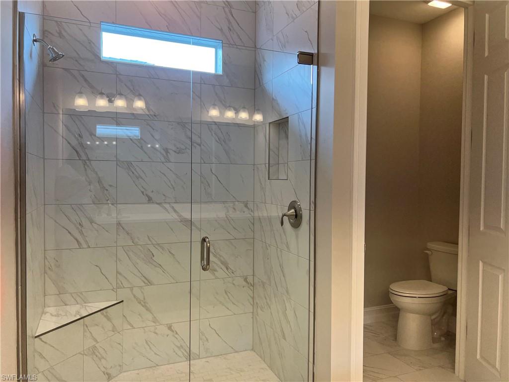 393 Deauville Loop Naples, FL 34114 - Photo 16 of 19 Full bath featuring toilet, marble look tiles, a stall shower, and baseboards