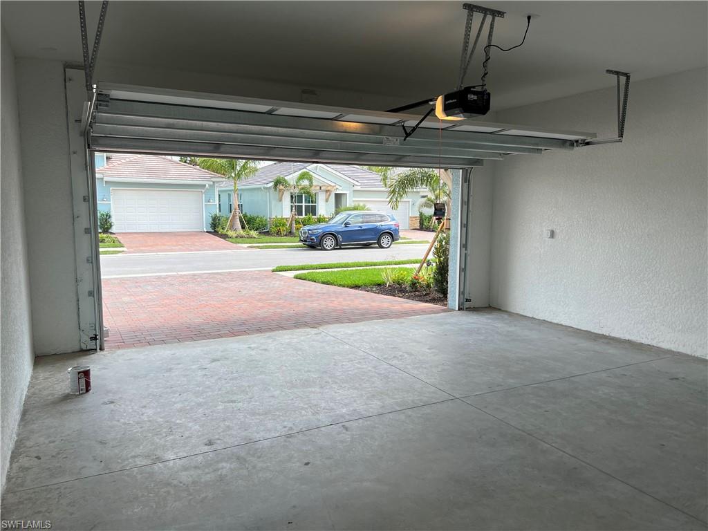 393 Deauville Loop Naples, FL 34114 - Photo 17 of 19 Garage with a garage door opener and a textured wall
