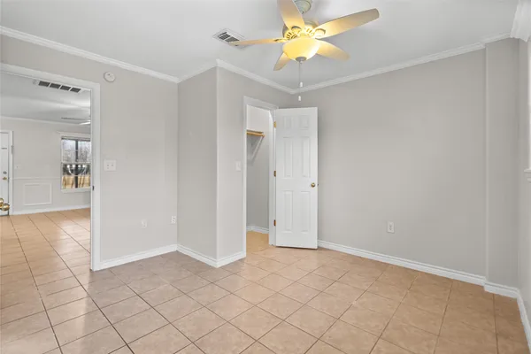 a view of an empty room and chandelier fan