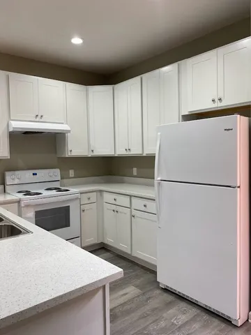 a kitchen with cabinets stainless steel appliances and wooden floor
