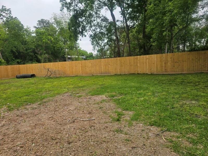 a view of a yard with a fence and trees