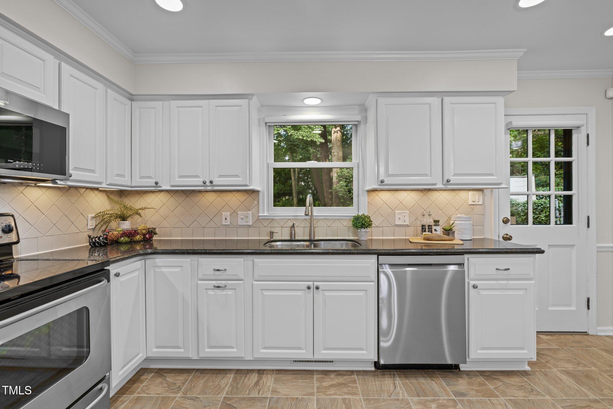 6925 Valley Lake Drive Raleigh, NC 27612 - Photo 11 of 50 a kitchen with granite countertop white cabinets and window
