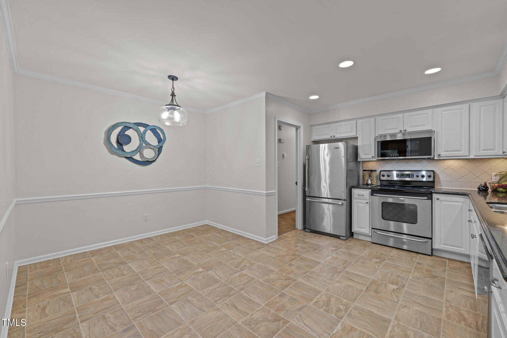 6925 Valley Lake Drive Raleigh, NC 27612 - Photo 9 of 50 a kitchen with granite countertop a stove a sink and a refrigerator