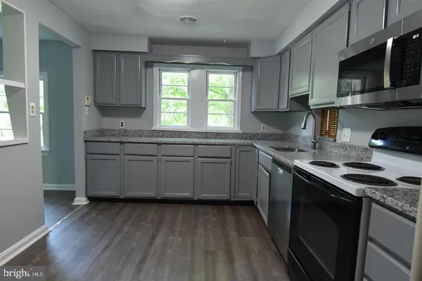 a kitchen with a sink stove cabinets and wooden floor