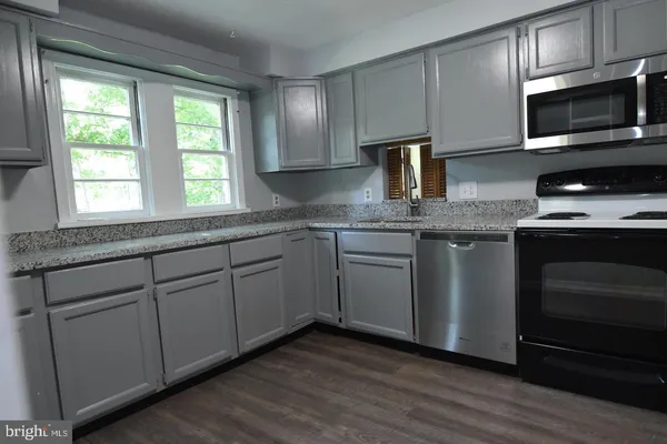 a kitchen with stainless steel appliances granite countertop a sink a stove a microwave and wooden cabinets