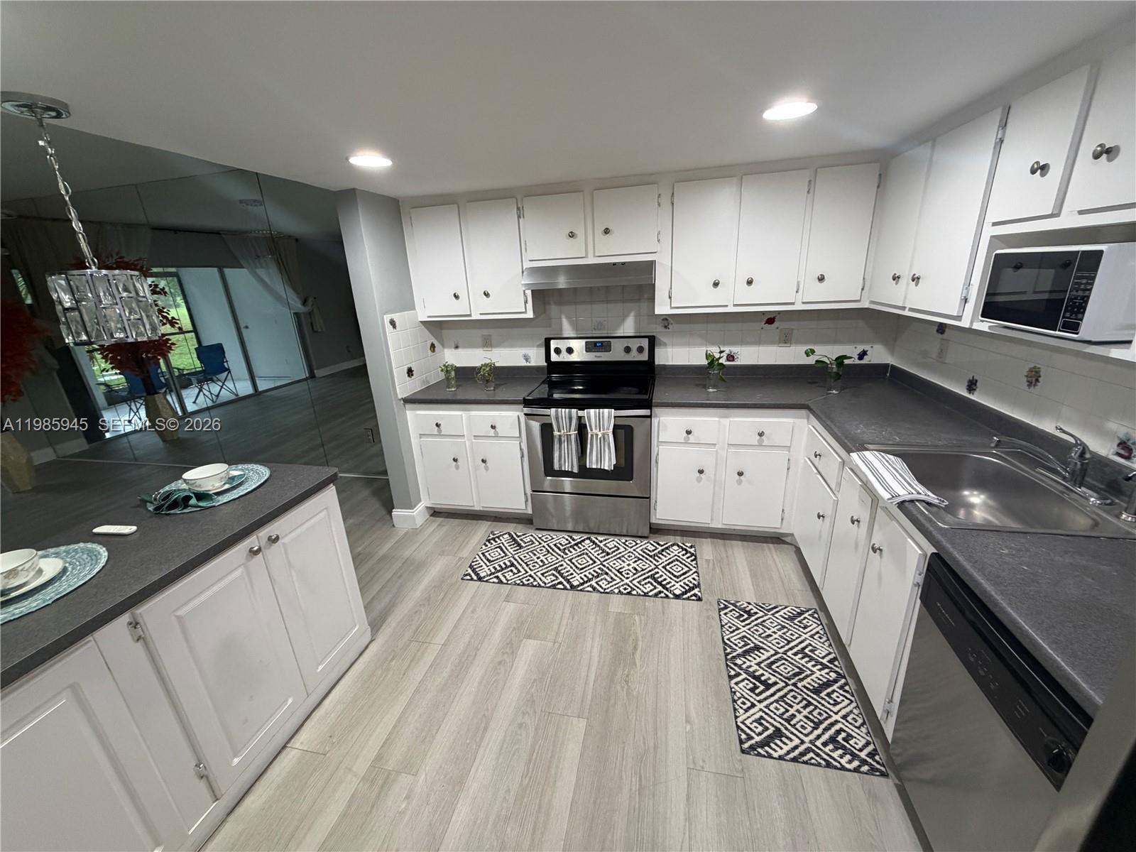 3962 Inverrary Drive, Unit A3 Lauderhill, FL 33319 - Photo 11 of 42 a large kitchen with stainless steel appliances granite countertop a stove a sink dishwasher and a microwave