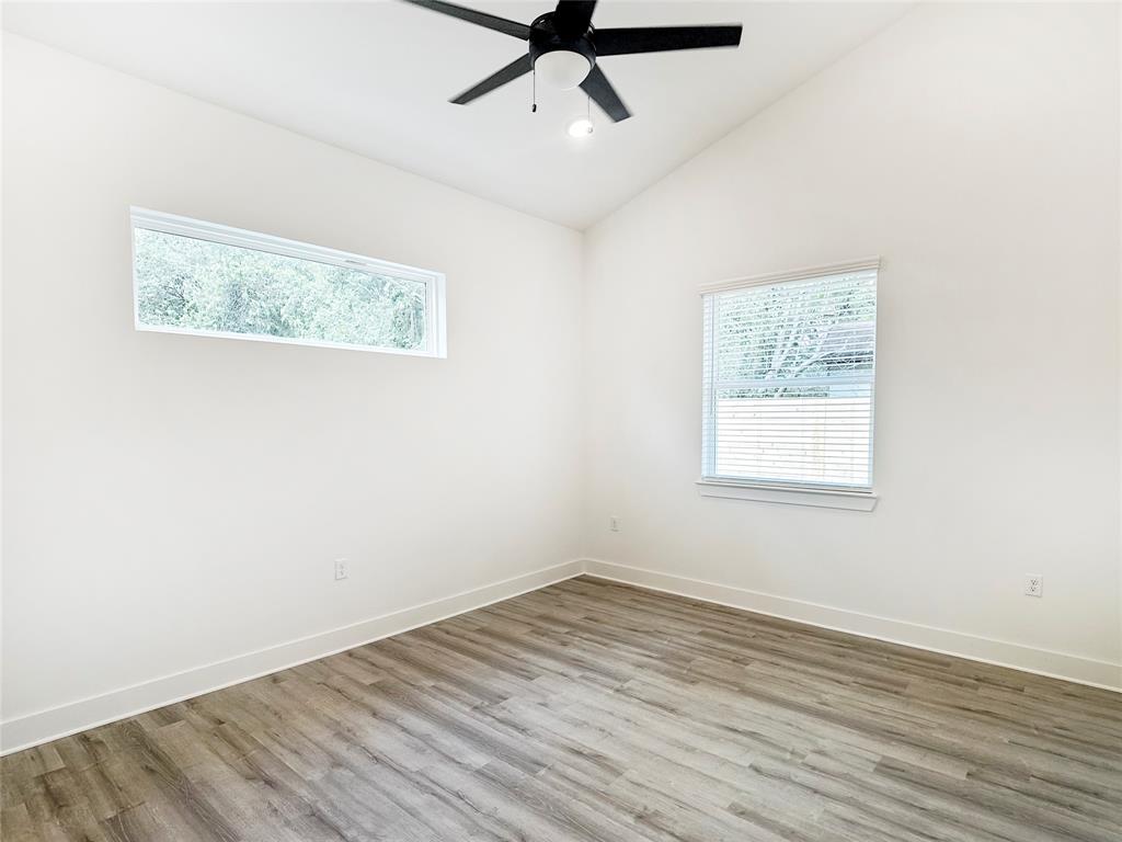 6107 Begonia Circle, Unit 2 Austin, TX 78741 - Photo 8 of 15 Unfurnished room featuring lofted ceiling, healthy amount of natural light, wood finished floors, a ceiling fan, and recessed lighting