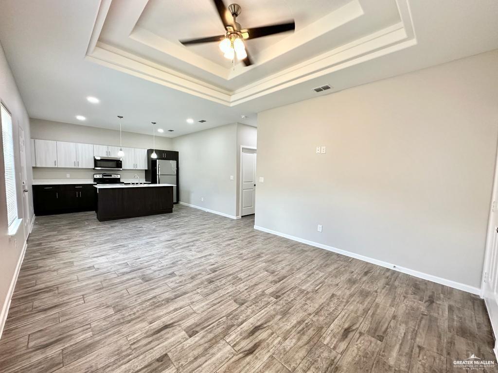 1002 Starr Street Mercedes, TX 78570 - Photo 6 of 17 a view of a kitchen with kitchen island a refrigerator wooden floor and ceiling fan