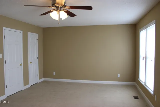 an empty room with a window and a chandelier fan
